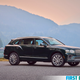 A green Bentley Bentayga SUV is parked in front of a lake.